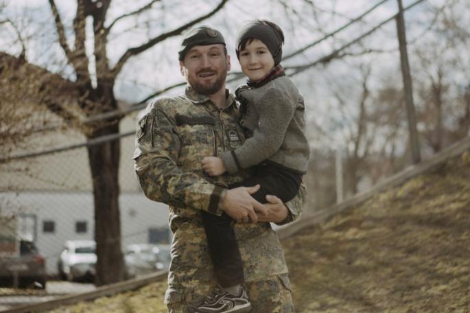 Ein lächelnder Soldat hält ein lächelndes Kind