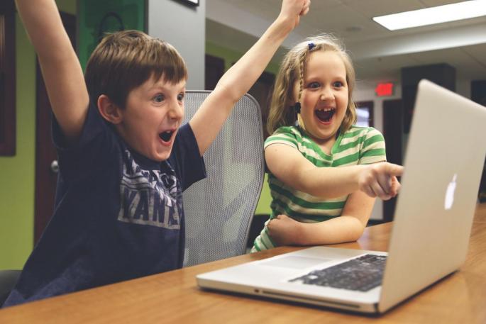 Symbolbild: Zwei Kinder jubelnd vor einem Laptop