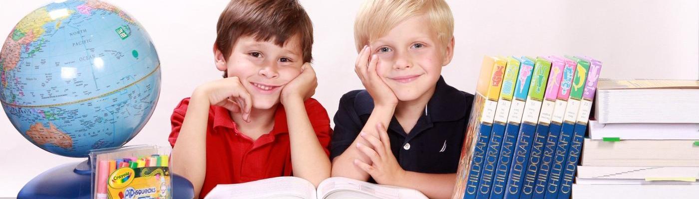 Symbolbild: zwei Kinder mit Schulsachen, Globus und Büchern