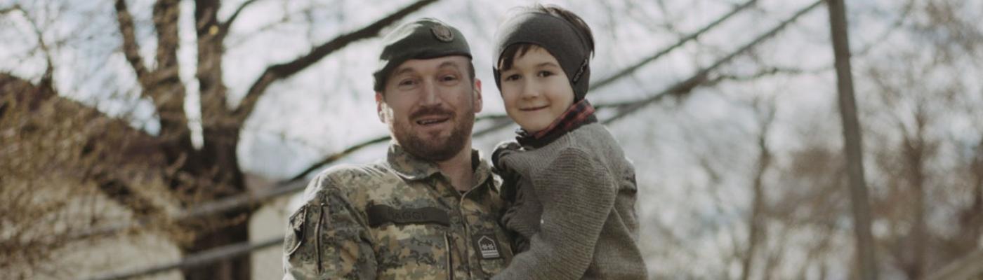 Ein lächelnder Soldat hält ein lächelndes Kind