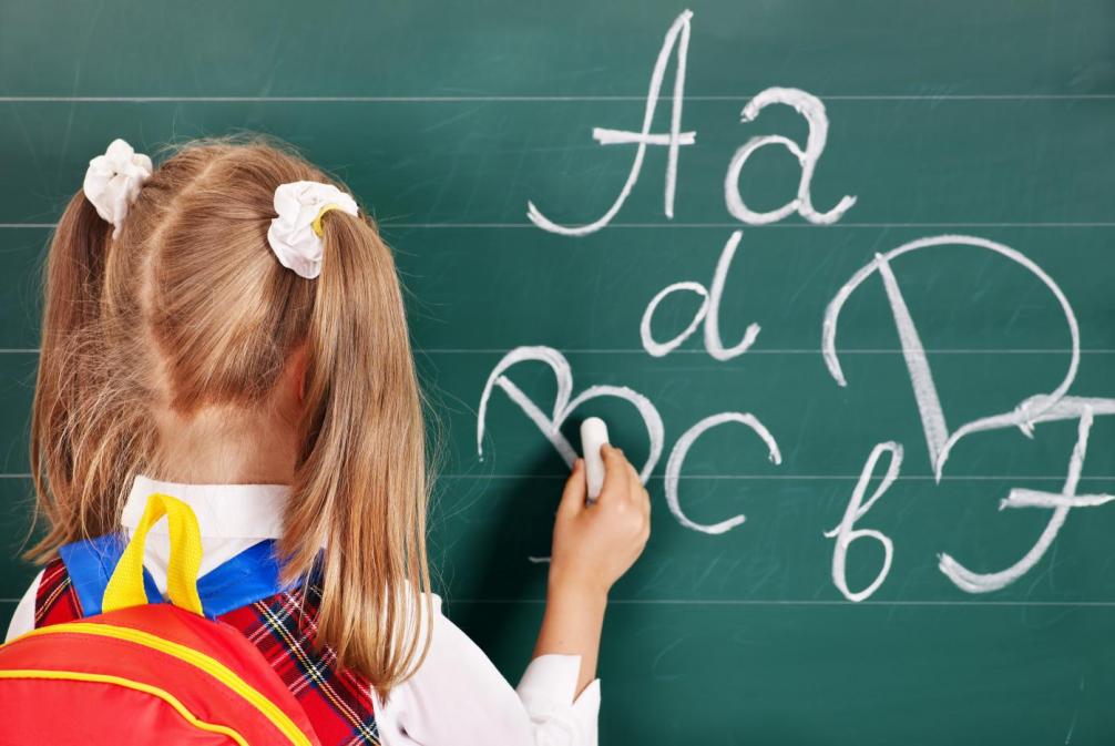 Mädchen schreibt Buchstaben auf die Tafel