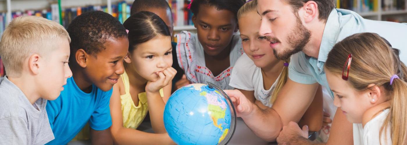 Symbolbild: Lehrperson mit Globus und Kindern